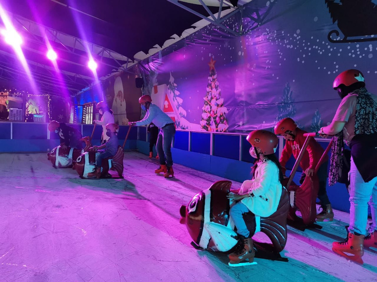 Niños patinando con pingüinos de apoyo en evento navideño